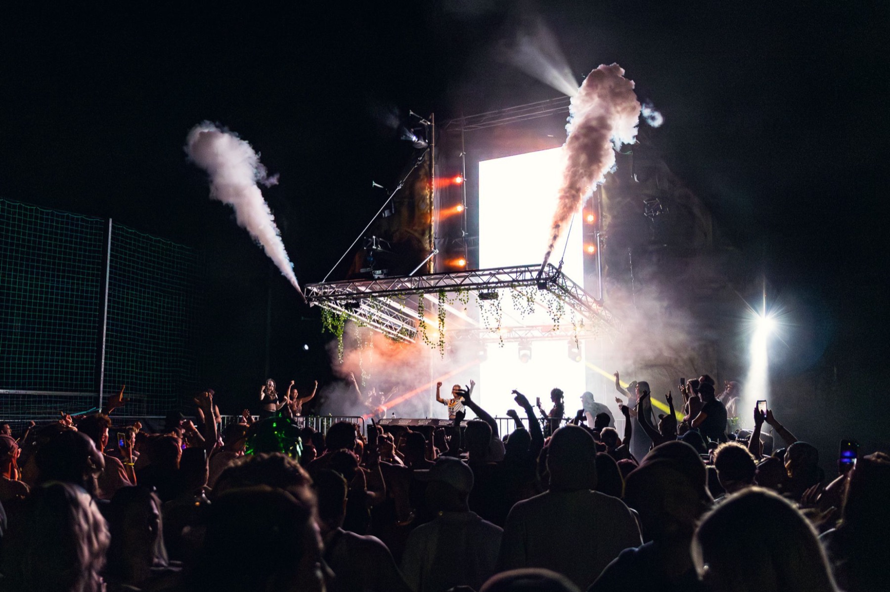 Festivalbühne bei Nacht mit Rauchfontänen, Publikum mit erhobenen Händen