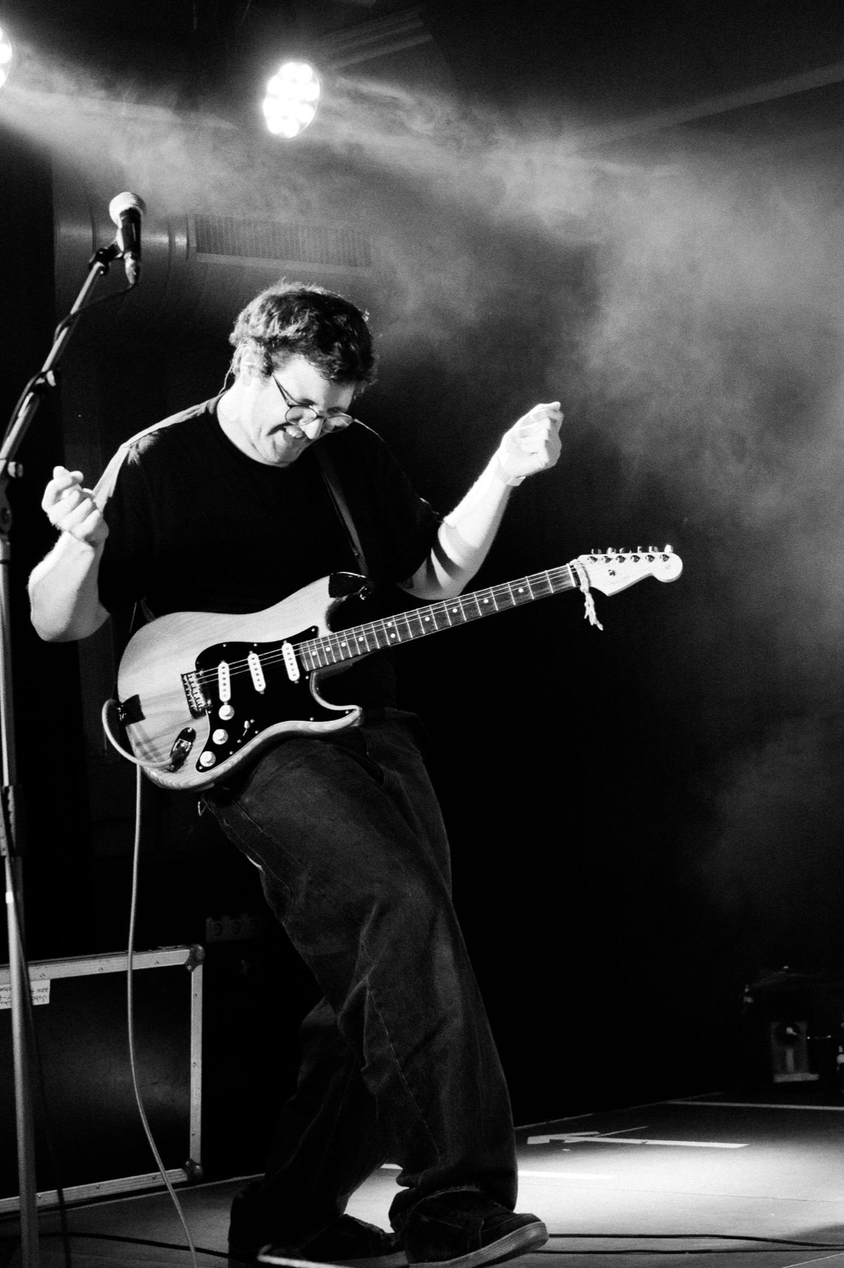 Gitarrist tanzt mit E-Gitarre auf der Bühne, Nebel und Scheinwerfer