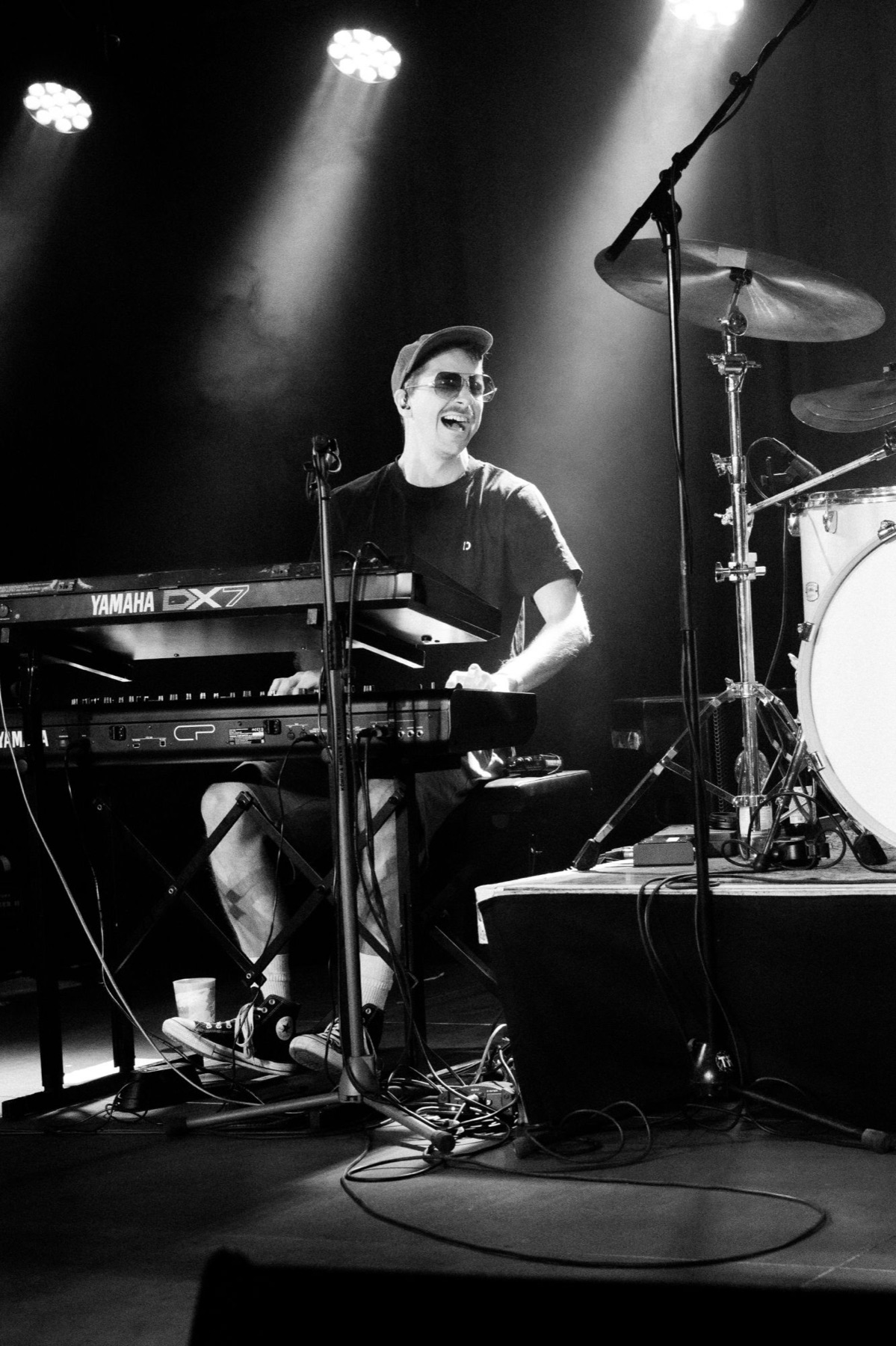 Keyboarder mit Sonnenbrille lachend an zwei Keyboards im Scheinwerferlicht